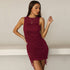 A woman modeling a burgundy sleeveless ruched mini dress with adjustable side ties posed against minimalist white backdrop