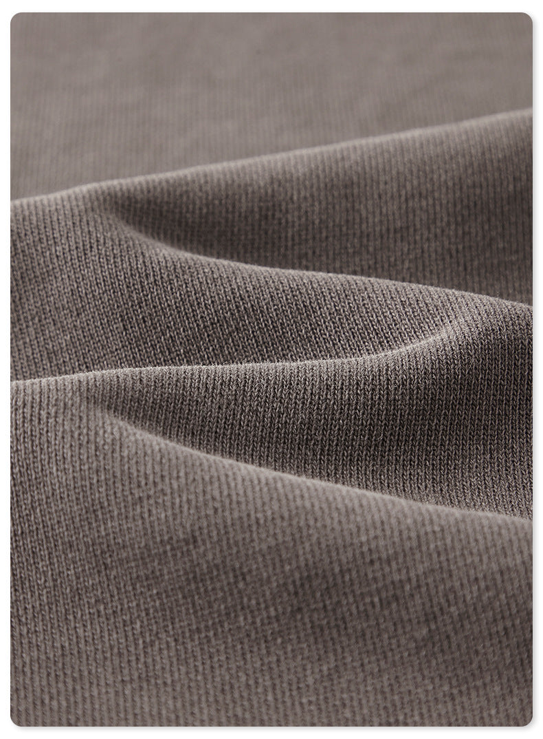 Close-up of charcoal gray cotton fabric showing knit texture and folds against white background