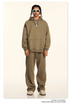 Model wearing tan hoodie and sweatpants with white sunglasses and silver tooth pendant necklace