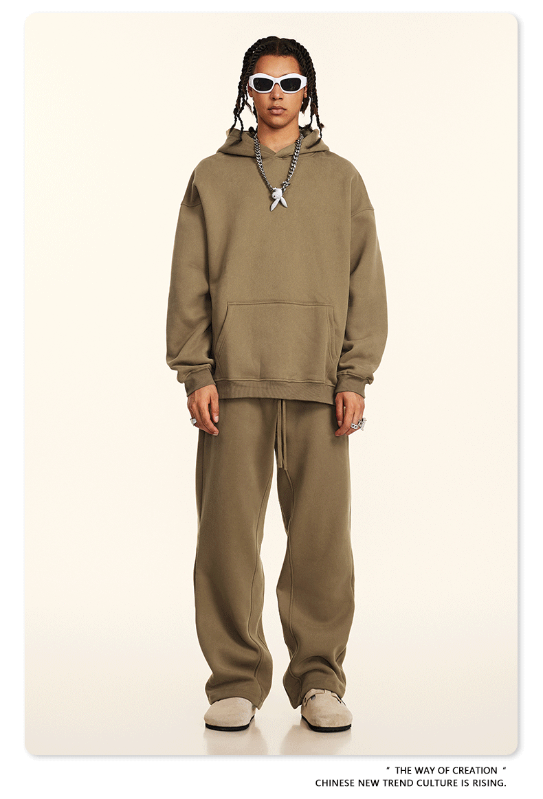 Model wearing tan hoodie and sweatpants with white sunglasses and silver tooth pendant necklace