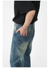 Close-up side view of model's hand in back pocket of vintage-wash jeans, showing denim texture and relaxed fit