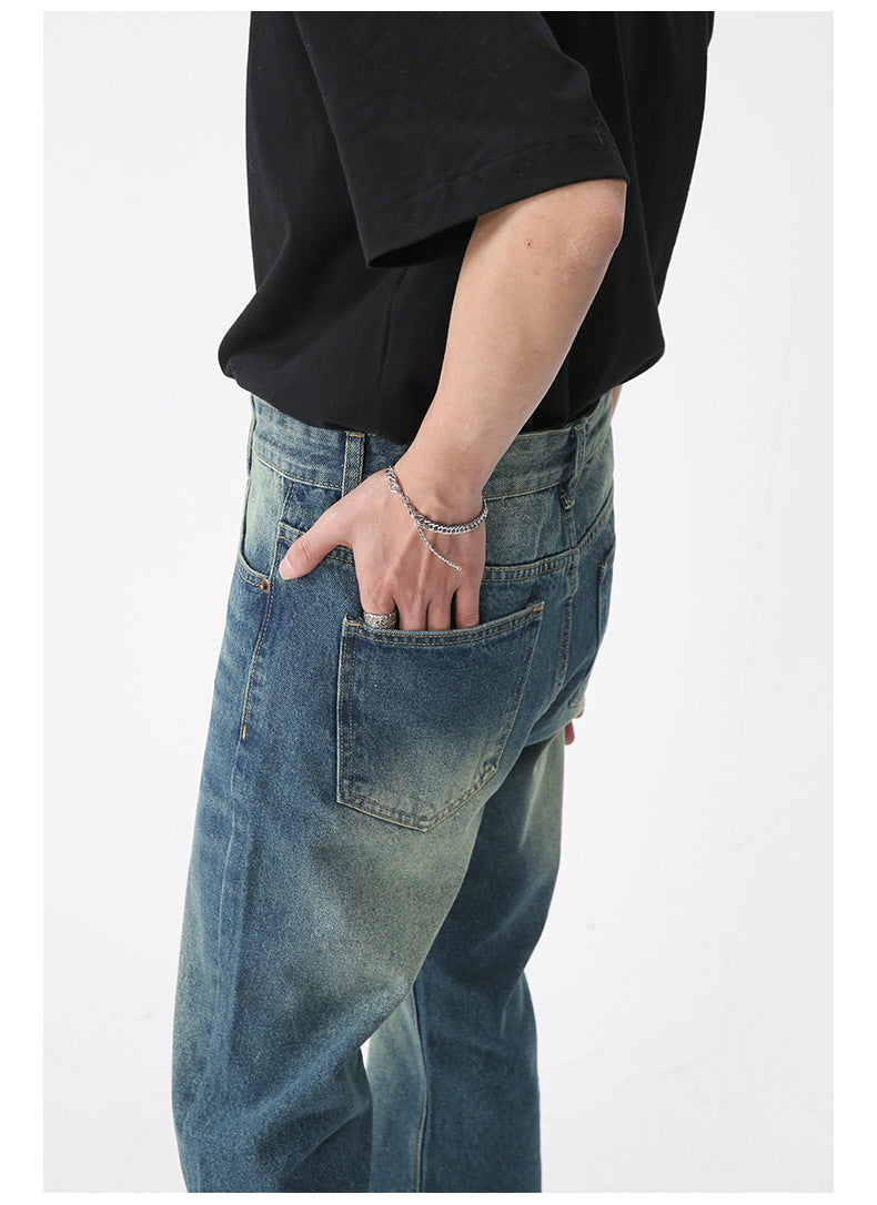 Close-up side view of model's hand in back pocket of vintage-wash jeans, showing denim texture and relaxed fit
