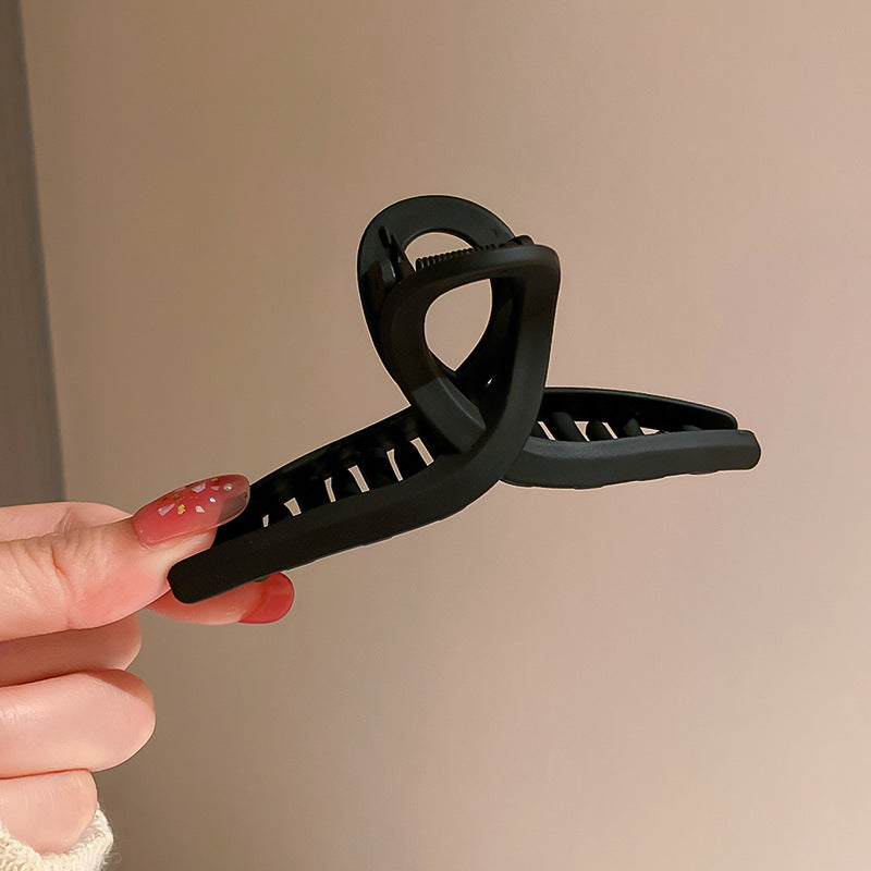 Geometric black hair clip with curved design, offering modern hair accessory aesthetic