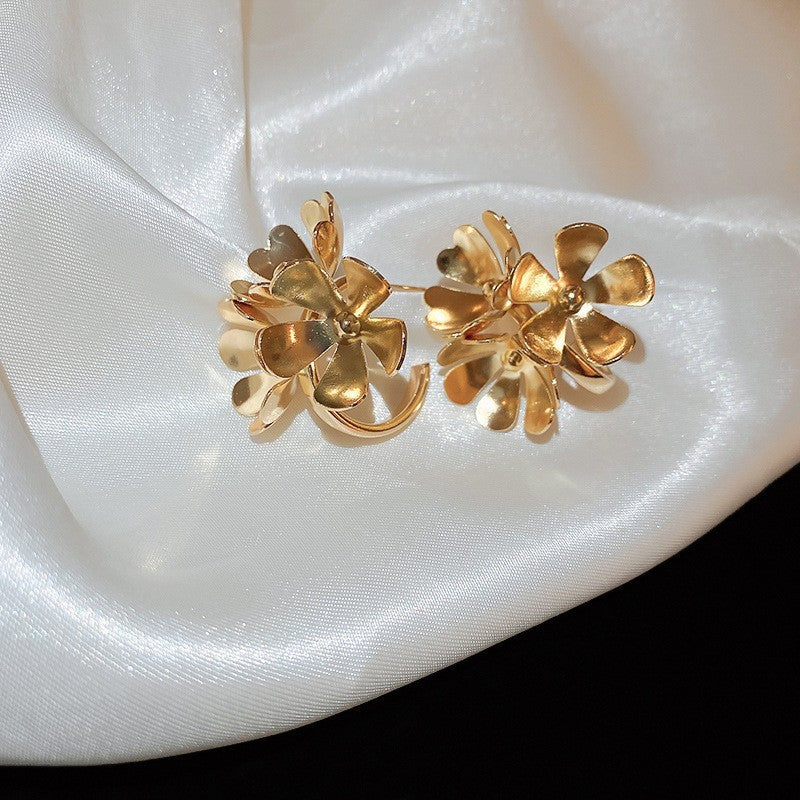 Gold Cluster Flower Earrings – Intricate gold floral earrings with multiple layers of delicate, petal-shaped elements, set against satin fabric