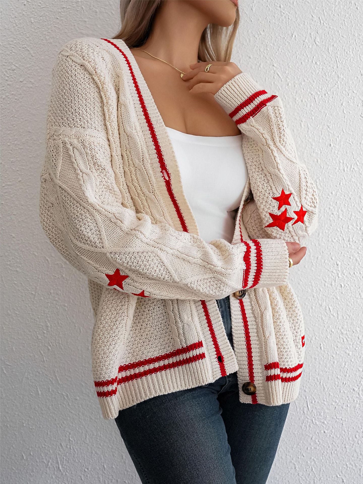 Cream cardigan with red stripes and star accents, layered over white tank for sporty-chic outfit
