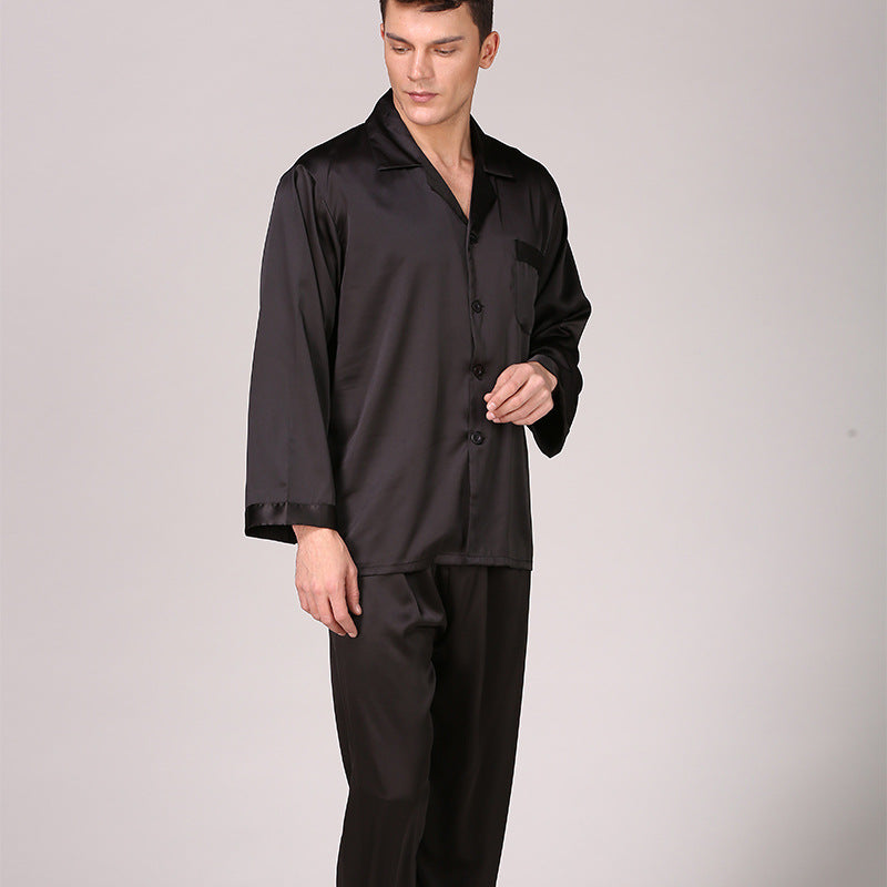Side view of man in black satin pajama set with button-front top and relaxed pants on light gray background