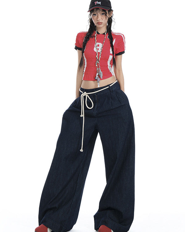 Model standing in dark denim wide-leg jeans, red crop top, and rope waist detail.