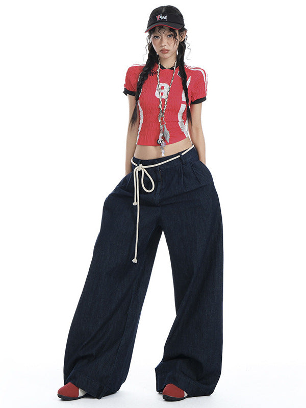 Model standing in dark denim wide-leg jeans, red crop top, and rope waist detail.