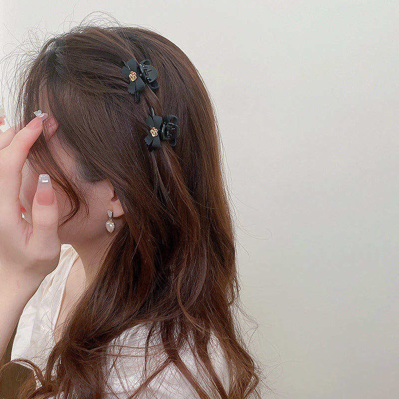 Two black bow clips styled in brown hair