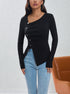 Front view of black asymmetric top featuring pearl-like buttons and modern design, paired with jeans