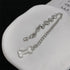 Silver dog bone bracelet laid flat on white background
