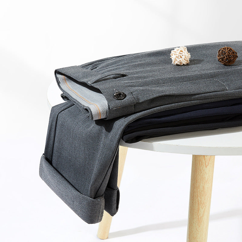 Gray dress pants neatly folded on white table with decorative elements, showing cuff detail with button closure