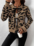 Model holding coffee cup, wearing tan and black animal print cardigan with front ties, black pants