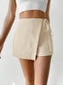 Close-up detail of cream wrap skort showing textured fabric and side tie closure, styled with white cropped tank