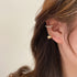 Side view of pearl and gold ear cuff with heart charm against dark hair
