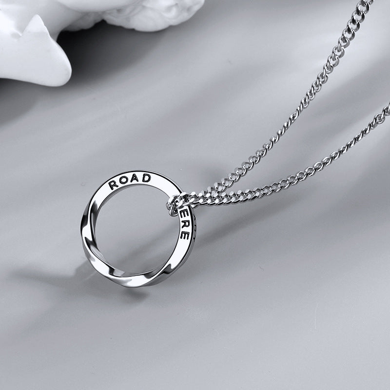 Close-up of silver twisted ring pendant with 'ROAD' text engraving