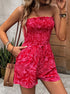 Woman wearing a red strapless romper with pockets, accessorized with bracelets and a woven handbag.