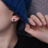 Close-up of silver and black huggie hoop earring worn with blue sweater