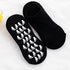 Pair of black ankle socks with white footprint grip pattern, one showing sole design and one showing top side against white background