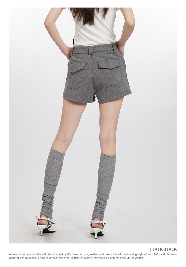 Back view of gray shorts with flap pockets, shown with white top and knee-high socks with heels