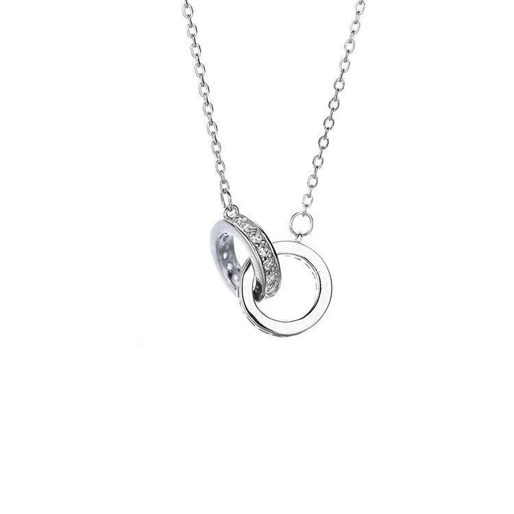 Product photo of silver double ring pendant necklace with diamond accents on white background showcasing modern design