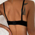 Back view of a black bra with adjustable straps and hook closure, showing tattoo on model's shoulder against white textured background