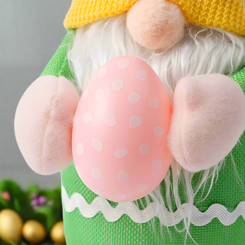 Close-up of a green Easter gnome plush holding a pink polka-dotted egg, highlighting soft plush hands and white faux fur beard.