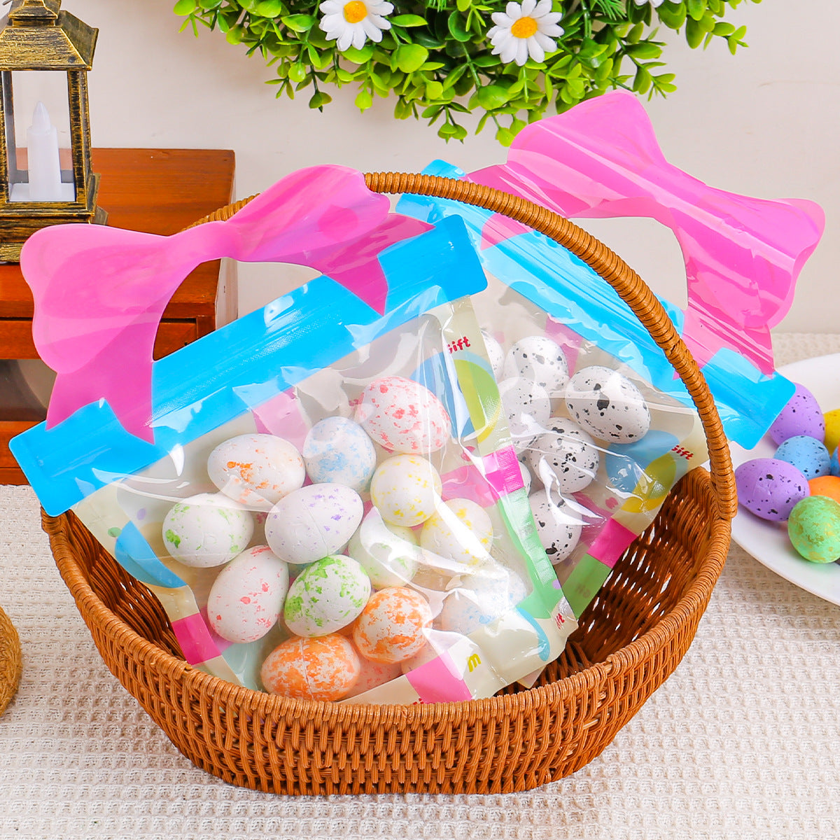 A wicker basket with resealable gift bags filled with speckled eggs in white, orange, and pastel shades, decorated with pink bows.