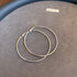 Pair of silver hoop earrings with clasp closure displayed on gray Taylor-Joy surface, showing classic design