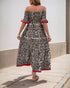  Back view of a woman in an off-shoulder leopard print maxi dress, showing the flowy silhouette and red trim details.