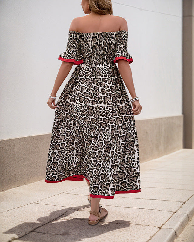  Back view of a woman in an off-shoulder leopard print maxi dress, showing the flowy silhouette and red trim details.