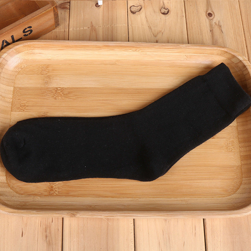 Black cotton crew sock positioned on wooden tray with "Originals" box in background