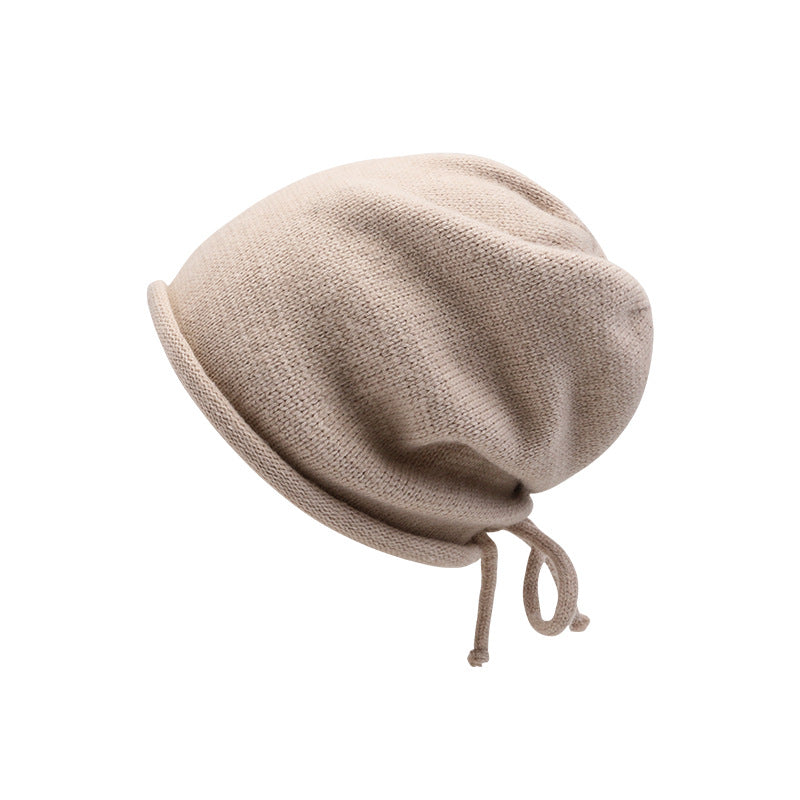 Beige knit slouchy beanie hat with drawstring detail and ribbed texture