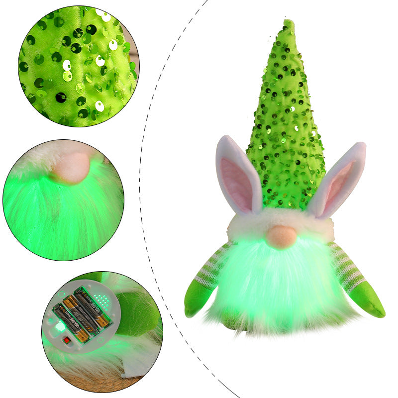 Close-up of a green LED bunny gnome plush toy with a sequined hat, featuring glowing beard and battery compartment.