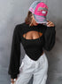 Woman in black cutout hoodie and white cargo pants wearing pink and gray vintage baseball cap that partially covers face