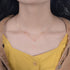 A woman wearing gold diamond cross necklace with delicate chain against yellow blouse, showing how pendant rests at collarbone