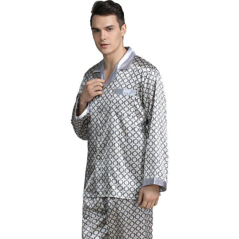 Model standing, adjusting collar of silver/white circular patterned silk pajamas against gray backdrop