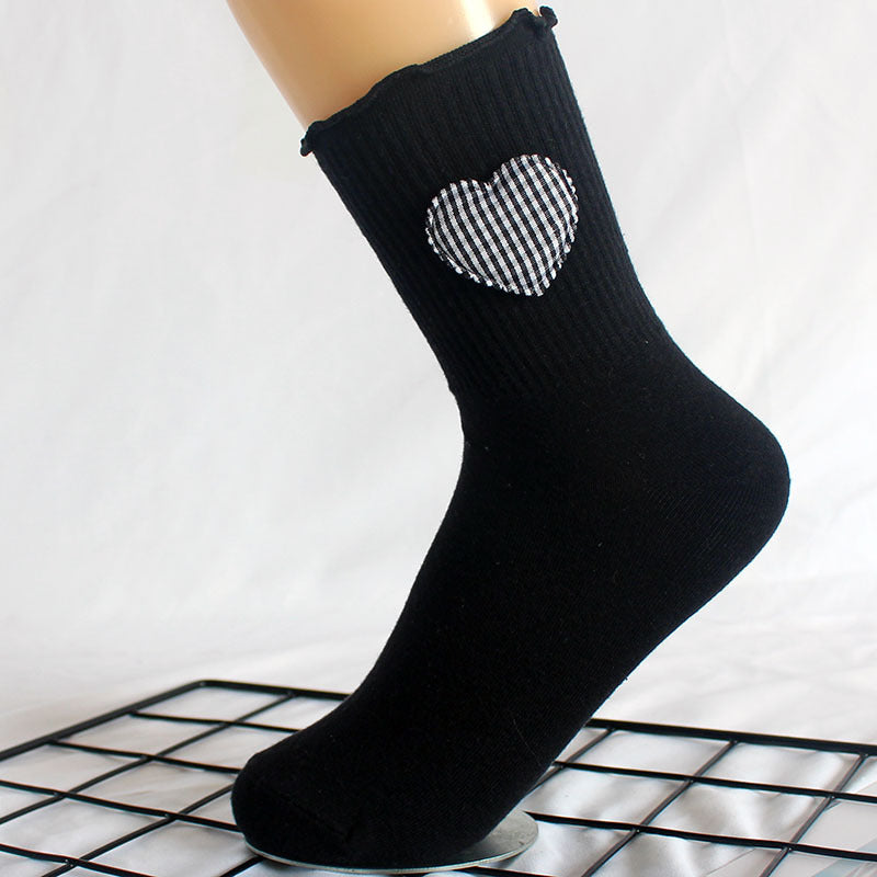 Black crew sock with gingham heart patch shown on a mannequin foot against grid background