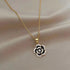 Delicate gold chain necklace with black and crystal flower pendant on silk background