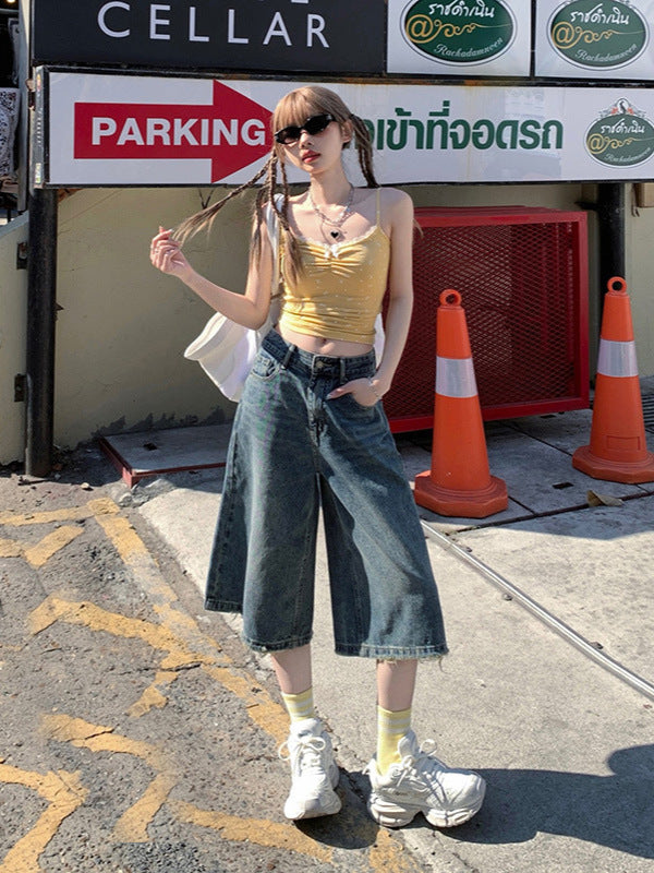 Front angle, hand-in-pocket shot – Retro-style denim shorts with knee crop and street-style edge.