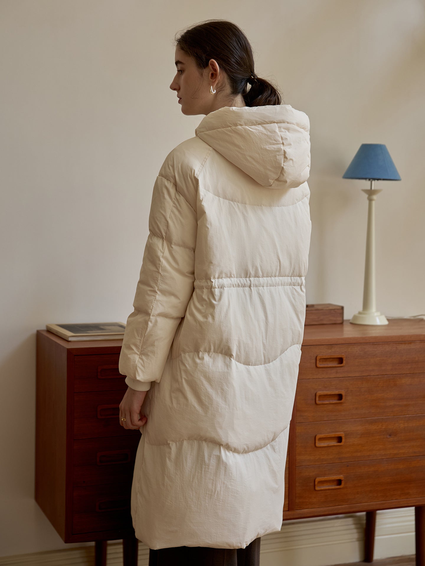 Back view of white quilted puffer coat showing cinched waist detail and hood construction