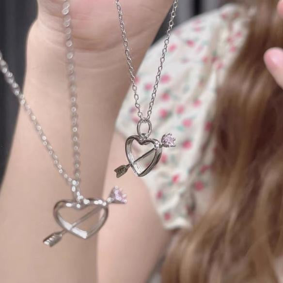 Two matching silver heart and arrow necklaces shown being worn, floral print dress visible