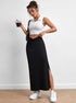 Black long skirt with twisted waistband, worn by a woman in a white crop top, holding a drink, with white sneakers and messy updo