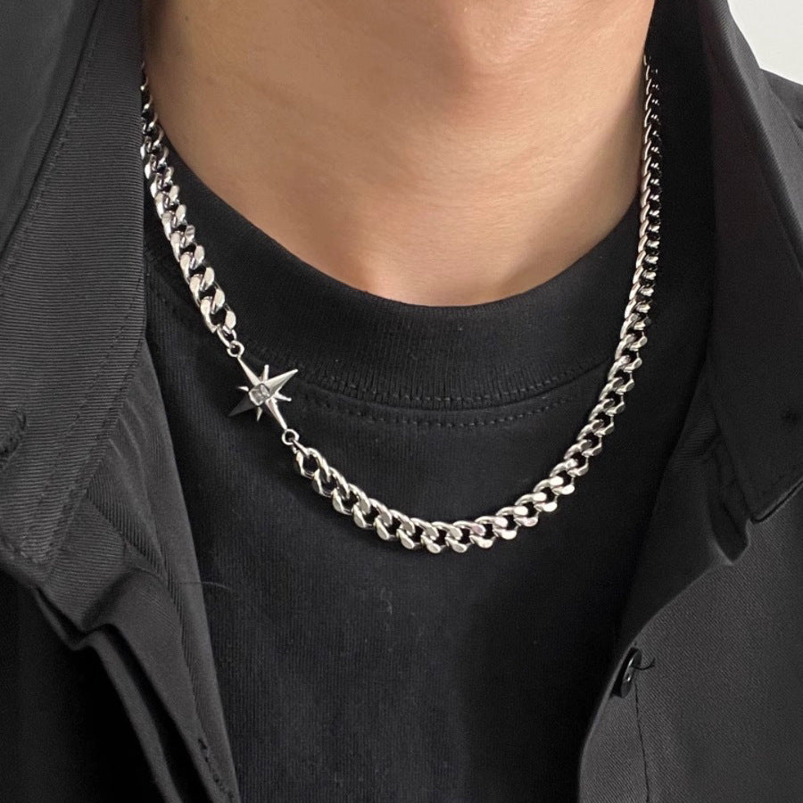 Close-up of Cuban chain necklace showing detailed view of starburst charm with crystal center against black clothing