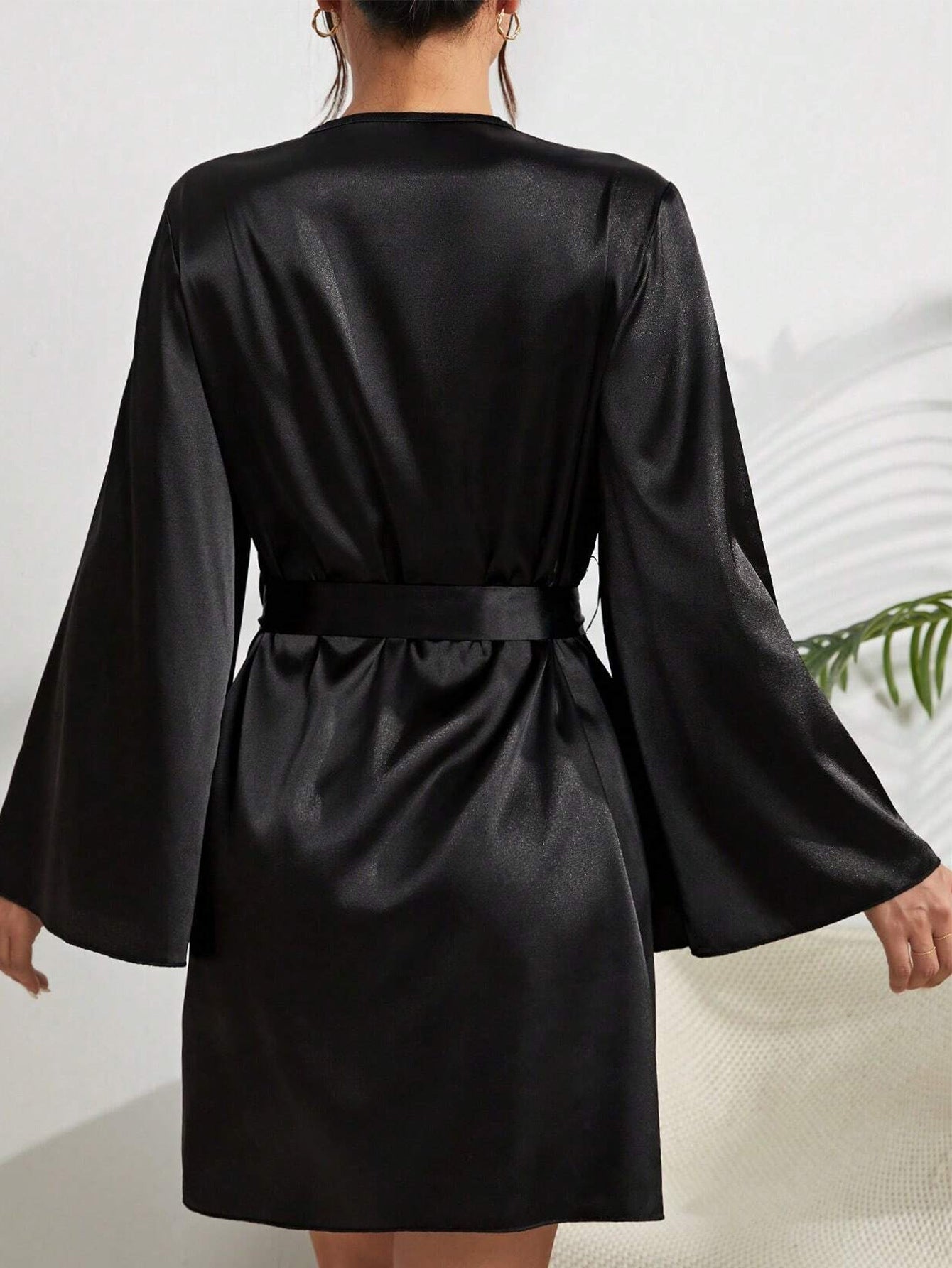 Back view of black silk robe showing bell sleeves and tied waist belt against white background
