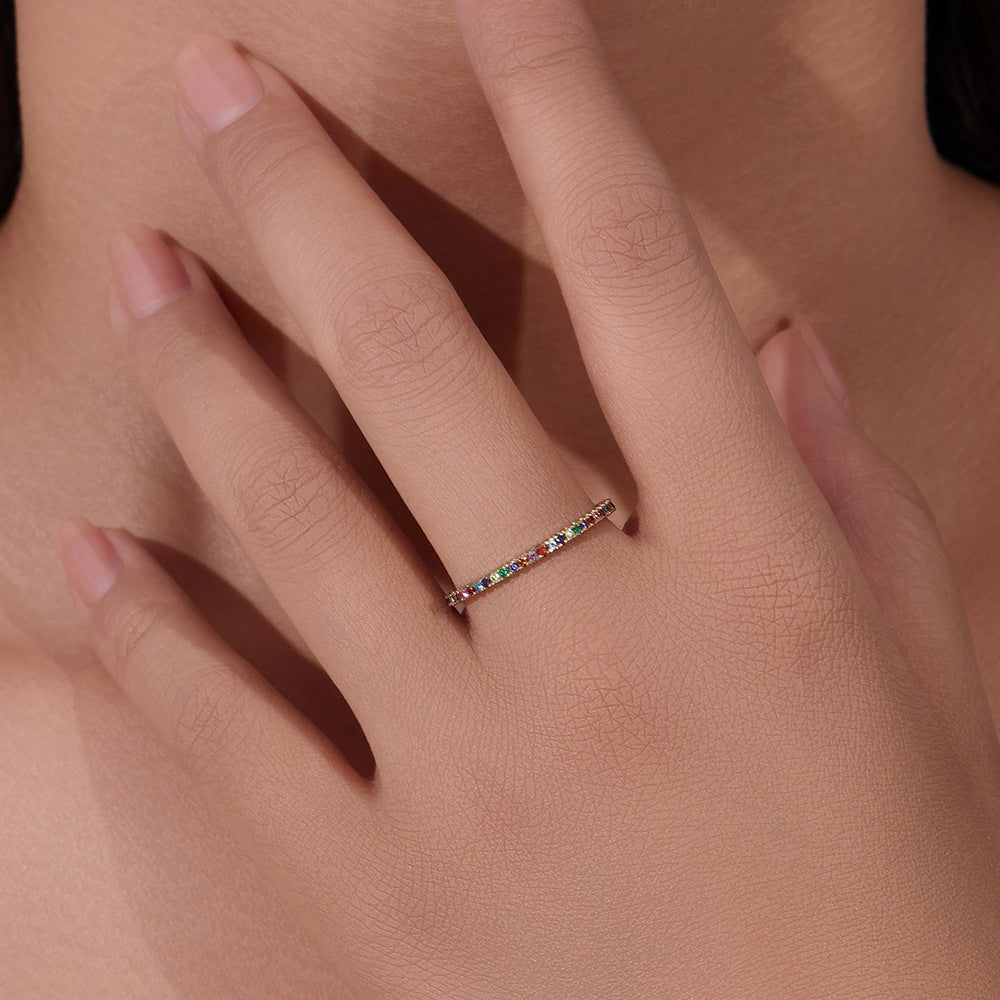 Close-up of multicolor gemstone ring on hand showing delicate prong setting and mixed colored stones