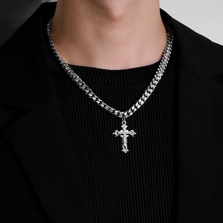 Silver cross pendant necklace with a Cuban link chain, styled over a black outfit
