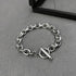 Silver chain bracelet with a toggle clasp resting on a dark surface.