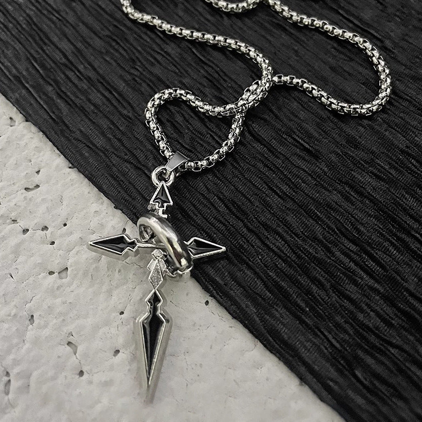 Silver cross pendant necklace with black enamel detail on sturdy box chain arranged on contrasting black and white surfaces