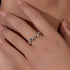 A woman displaying gold bezel-set rainbow gemstone bubble ring on her hand against neutral skin background